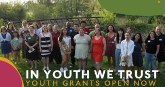 Group of people of all ages outdoors smiling at the camera. Text reads: In Youth We Trust youth grants open now